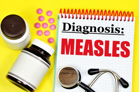 Measles is an infectious viral disease. The inscription of the diagnosis in the medical folder on the background of a stethoscope and medicines.の写真素材
