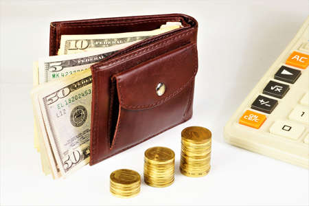 Cash dollars in your wallet. and coins in ascending order against the background of the calculator. The concept of a financial well-being strategy.の写真素材