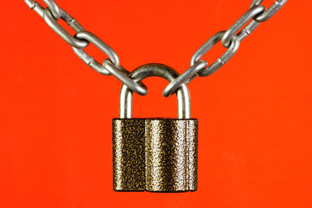 The chain is connected by a lock, on a red background. The concept of securing or connecting...