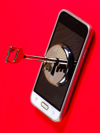 Smartphone data security. The key and the keyhole on the smartphone screen on a red background.の写真素材