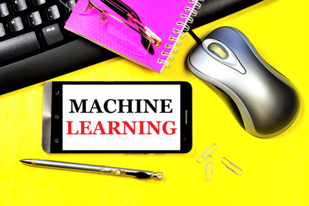 Machine learning. The inscription on the smartphone screen on the background of a computer keyboard, mouse and notepad for notes.の写真素材