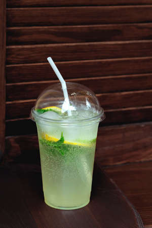 Cocktails in a plastic cup on a wooden background. Take Mojito takeaway, food delivery.の写真素材