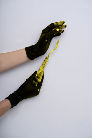 Minimalistic background in trending 2021 colors. Gray and yellow. Hands in gloves with a palette...