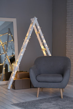 Details of a Scandinavian cozy interior in warm light beige. An armchair, a pillow in a silk pillowcase, a ladder in the lights, a mirror.の写真素材