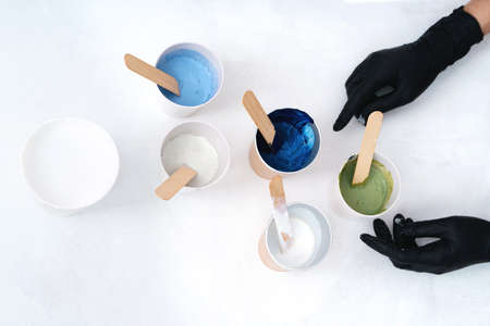 The process of creating a painting using fluid art technique. Hands with gloves and. Artistic...