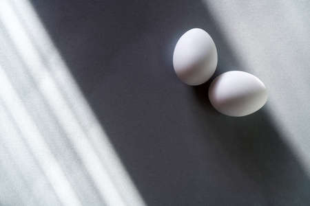 Eggs on a gray background, sun glare on the table. Easter background.の写真素材