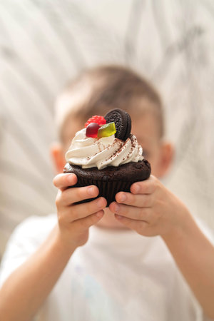 The boy holds a mini cake in his hands.の写真素材