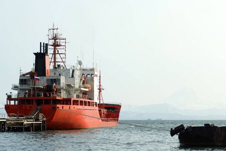 the red nave beside pier on background of the misty mountains.の写真素材