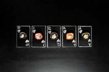 Royal Flush Poker cards with sushi roll pieces on dark chalkboard background. Asian rolls with black...