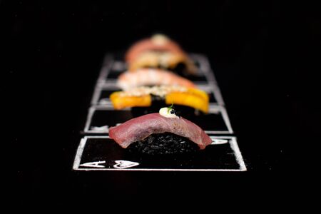 Hand drawn Poker cards, Japanese sushi nigiri with black rice and tuna tataki in focus on chalkboard. Near Different Asian meal. Ace of hearts card with Maguro nigiri.の写真素材