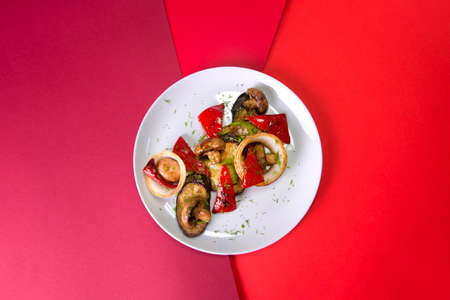 Top view of vegetarian dish. Mix of Grilled vegetables on gray plate. Colorful red background....