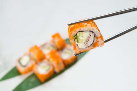 Close up of Sushi Roll piece wrapped in rice and flying fish roe (Tobiko, Masago caviar) hold in...