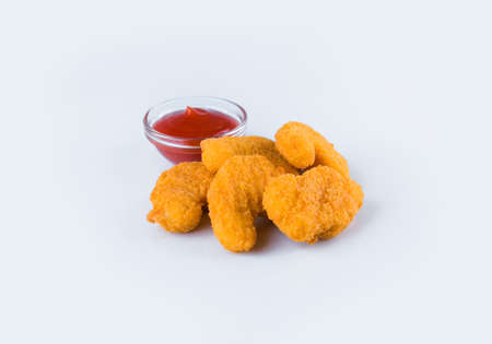 Chicken nuggets pieces isolated on white background, served with red tomato sauce in glass bowl. Fried meat fillet with sauce. Side view of Fast food dish. Menu isolationの写真素材