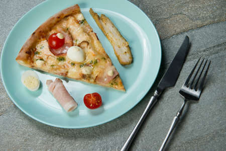Slice of chicken pizza with ingredients on plate. Fast food dish anthracite stone background. Piece...