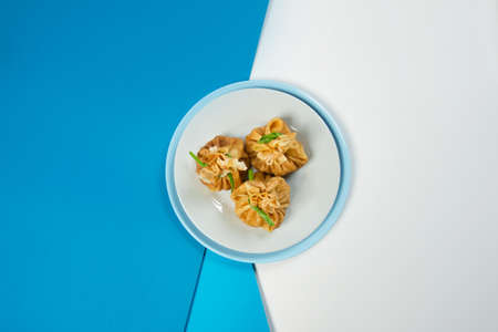 Top view of Holiday Russian starter dish blini with mushrooms inside. Traditional crepes appetizer with fresh spring onion scallions. Delicious new year Christmas dish on blue abstract backgroundの写真素材