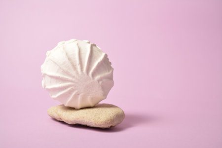 Piece of souffle served on sea stones on violet pastel background. Russian airy dessert zefir (zephyr) made of organic pectin and egg whites, similarly to marshmallow and meringue. Copy space imageの写真素材
