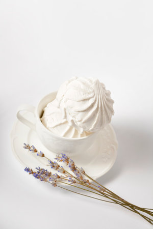 Vintage cup with two pieces of Russian traditional marshmallow dessert zefir (zephyr) souffle served with lavender herbs on plate isolated on white background. Similarly with Meringue Dessertの写真素材