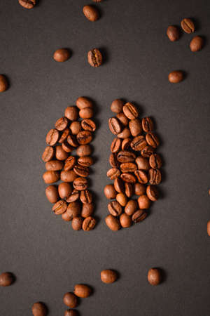 Vertical image of Coffee bean shape isolated on dark background. Coffee seed silhouette with scattered roasted high quality coffee beans on background. Aroma drinkの写真素材