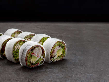 Crab meat, avocado, lettuce wrapped in daikon radish. Rice free sushi Served on concrete background....