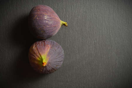 Top view of two Azerbaijani fig fruits. Exotic eastern fruit. Asian berry isolated on black stone background. Single object. Copy space imageの写真素材