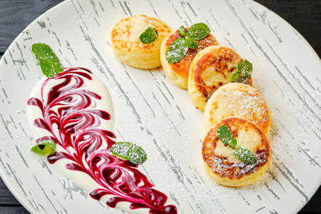 Traditional Russian dish Sirniki. Breakfast Goat cheese pancakes syrniki with sour cream, berry jam...