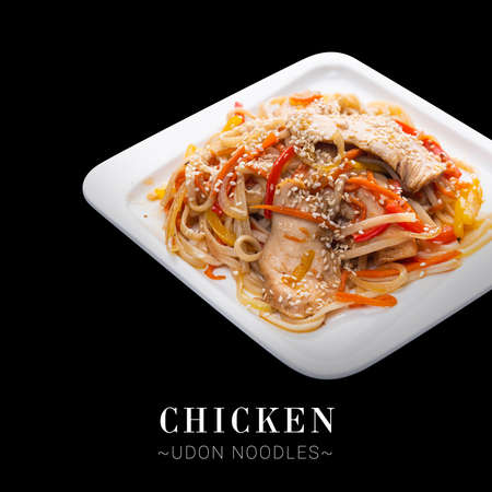 Side view of Meat Udon noodles with chicken, bell pepper, onions, carrots, tuna shavings served on square plate. Asian hot dish isolated on black background. Text space web banner designの写真素材