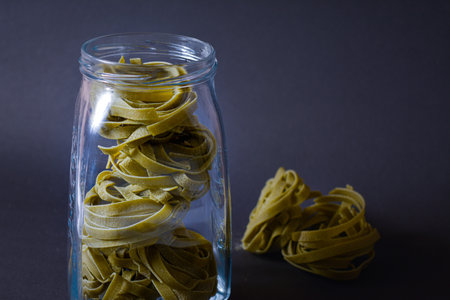 Raw green pasta served in glass bottle. Way of storage basil pasta noodles