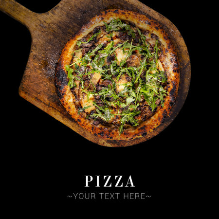 Top view of classic Italian uncut pizza with meat, mozzarella cheese and fresh arugula leaves served on baking shovel. Cheesy pizza isolated on black background with text and copy spaceの写真素材