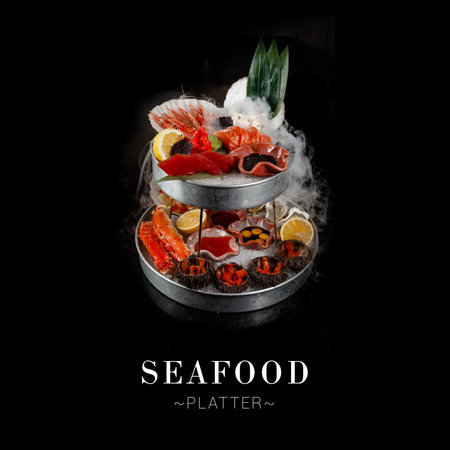Seafood platter isolated on black background. Plate with crab claws, salmon, tuna, shrimps, oysters, scallops, sea urchin served with citrus fruit slices and sauces Copy space Ready luxury menu bannerの写真素材