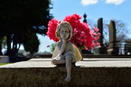 Young angel at grave site in front of flowersの写真素材