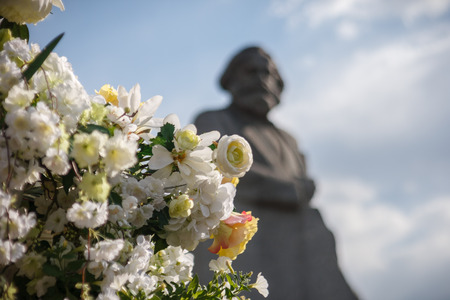 Artificial white and yellow flowers against a monument to Karl Marx during Moscow spring festivalのeditorial素材