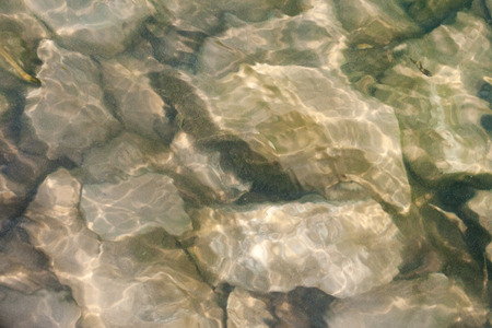 Stones under the mountain river water. Little fish  floats in the top right corner.の写真素材