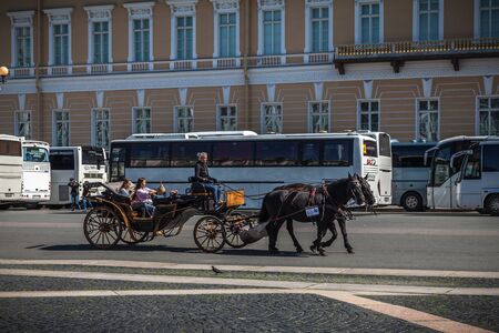 Saint Petersburg, Russia, August, 8, 2017 - Tourists ride in a carriage with horses on Palace square. Tourist buses are in the background.のeditorial素材