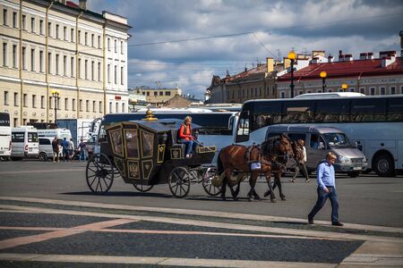 Saint Petersburg, Russia, August, 8, 2017 - Tourists ride in a carriage with horses on Palace square. Tourist buses are in the background.のeditorial素材