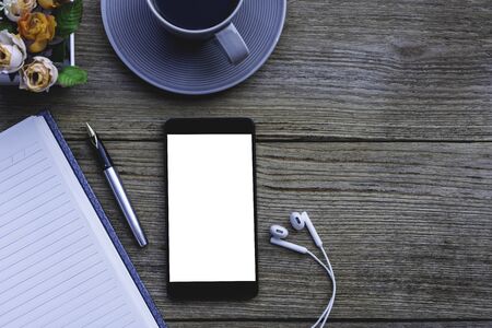Mobile smart phone, notebook and cup of coffee mock up design template isolated on old wooden table backgroundの写真素材