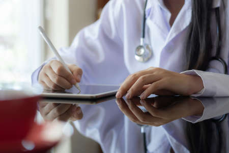 Young asian doctor woman work on tablet computer in medical room at office.の写真素材