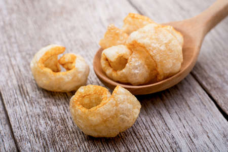 Fried pork snack ( pork rind, pork cracking ) isolated on wood table background.
