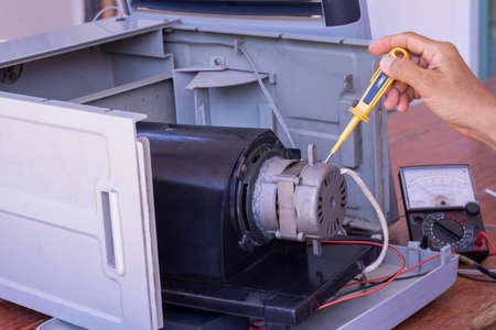 Technician man hand holding and using the screwdriver to repair the electronic evaporative fan....