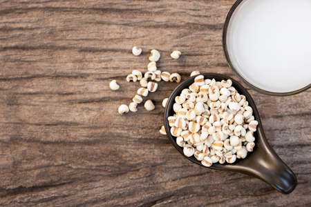 Closeup white Job's tears ( Adlay millet or pearl millet ) in black ceramic bowl and glass of millet...