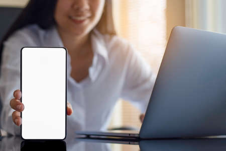 Mockup asian smiling woman hand holding and showing black mobile smart phone with blank white...