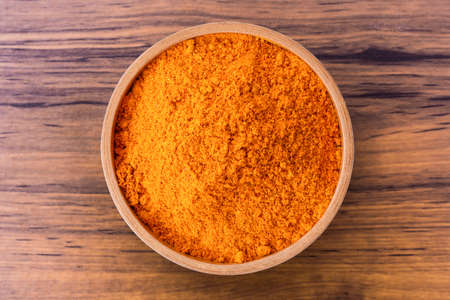 Turmeric ( known as curcumin, Curcuma longa Linn) powder in wooden bowl isolated on wood table background. Top view. Flat lay.の写真素材