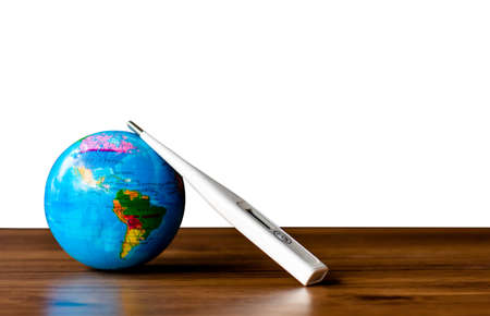 Mock up medical thermometer and global world model isolated on wooden floor on white background. Sign and symbol for takecare of health of planet, global warming, anti-virus covid-19 concept.の写真素材