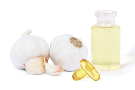 Garlic bulb with glass bottle of essential extract oil and capsule gel supplement isolated on white background. Healthy food or herbal natural medicine plant concept.の写真素材
