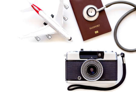 Mockup image of medical stethoscope, passport book, airplane model, camera isolated on white background. Business trip and travel insurance, leisure time, immigration concept. Top view. Flat lay.の写真素材