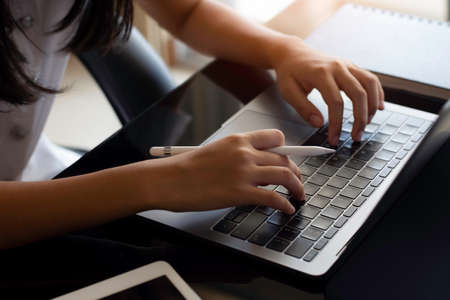 Businesswoman or female student hands typing on laptop computer keyboard with digital tablet on the desk at office. Online working, e learning or telework concept. Top view.の写真素材