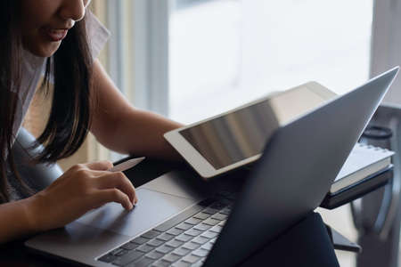 Young happy smiling asian business woman or female student working on laptop computer with digital...