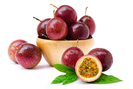 Close-up passion fruit ( Maracuya ) in wooden bowl and cut in half slice with green leaves isolated on white background .