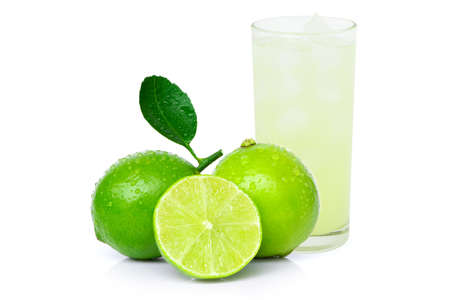 Closeup lemon juice in glass and pile of green lime fruits with leaf isolated on white background. Healthy drinks concept.の写真素材