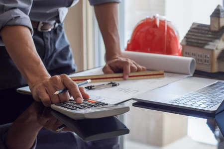 Architect man or male engineer hand using calculator and work on architectural project with laptop...