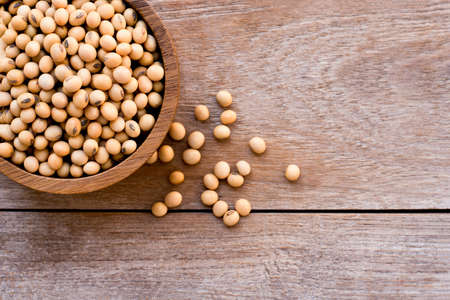 Closeup soy beans in wooden bowl  isolated on wood table background   . Overhead view. Flat lay.の写真素材